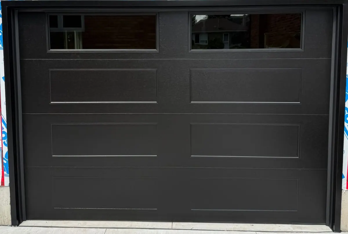 Black long-panel double garage door with top windows on a new build — GTA
