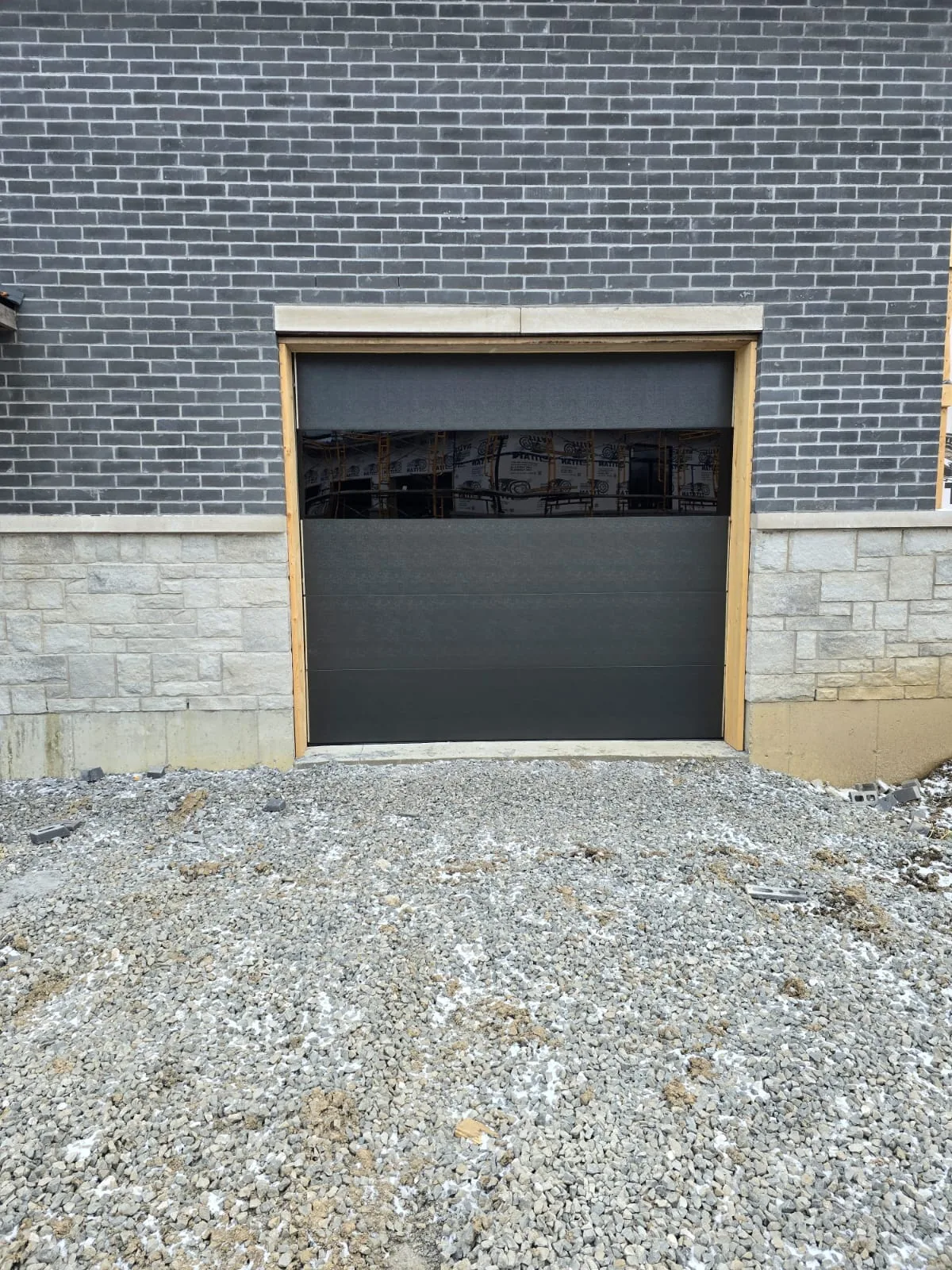 Black modern flush-panel double garage door with our technician on-site — GTA