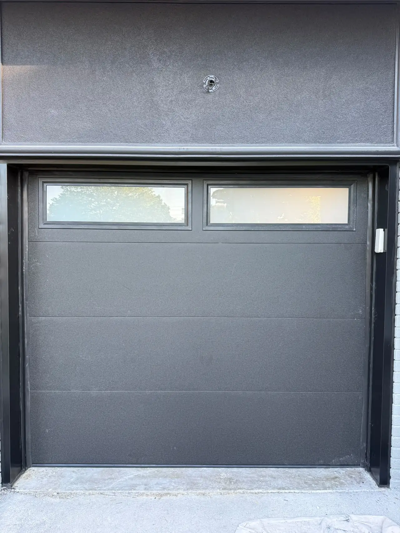 Grey modern flush-panel garage door with top windows — GTA