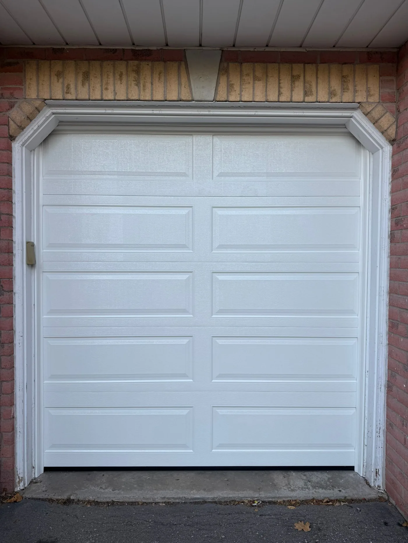 White long-panel single garage door on a brick home — GTA